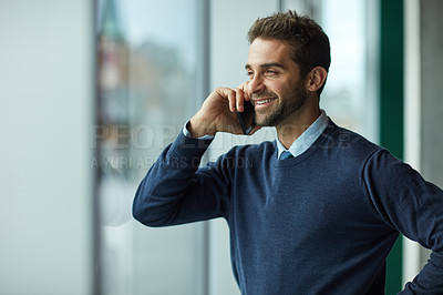 Buy stock photo Cropped shot of a handsome young businessman standing indoors alone and using his cellphone