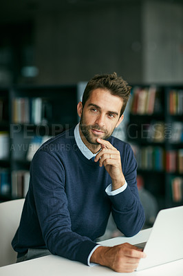 Buy stock photo Cropped shot of a handsome young businessman sitting in a library and looking contemplative while using a laptop