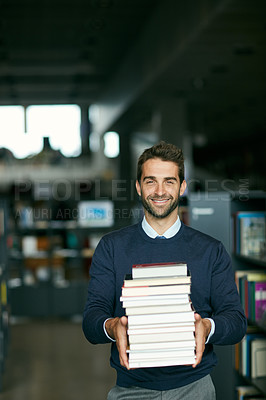 Buy stock photo Cropped portrait of a handsome young businessman standing alone in a library and carrying a pile of books