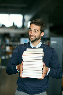 Buy stock photo Cropped portrait of a handsome young businessman standing alone in a library and carrying a pile of books