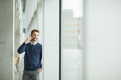 Buy stock photo Cropped shot of a handsome young businessman standing indoors alone and using his cellphone