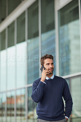 Buy stock photo Cropped shot of a handsome young businessman standing alone outside and using his cellphone during the day