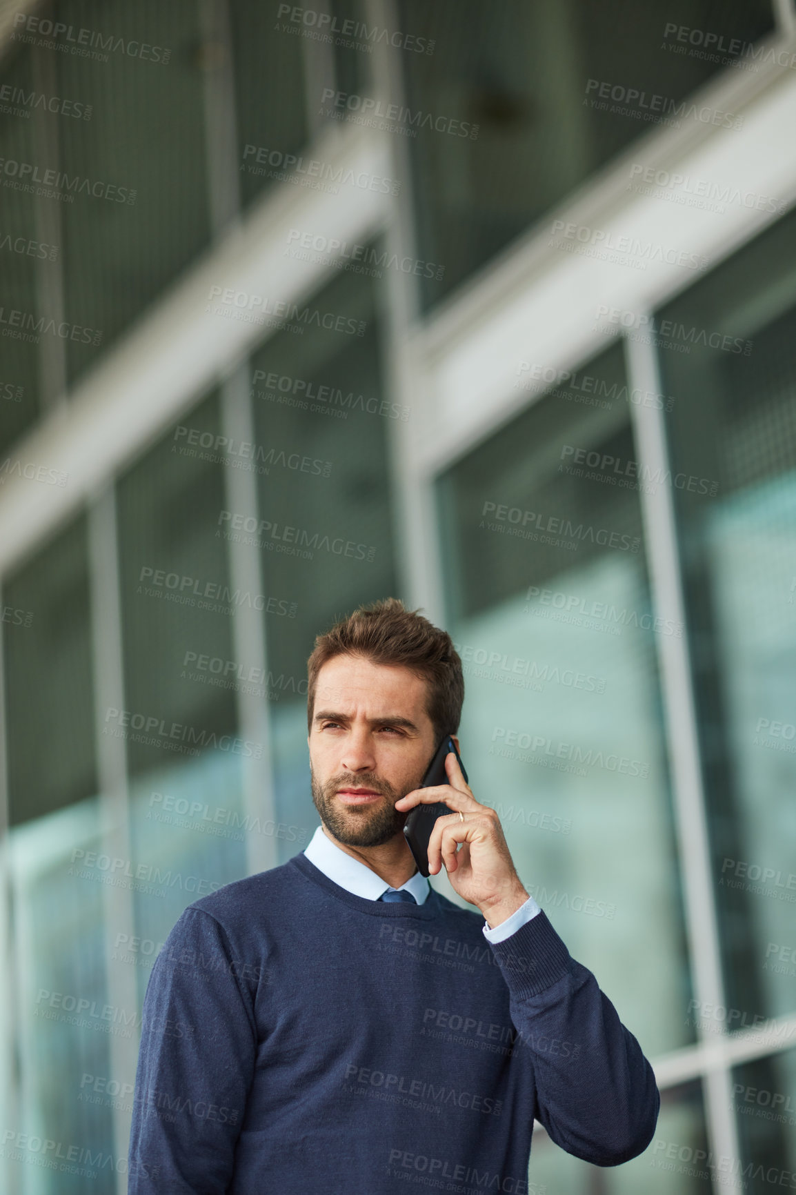 Buy stock photo Cropped shot of a handsome young businessman standing alone outside and using his cellphone during the day