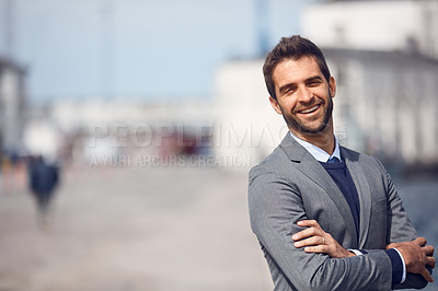 Buy stock photo Cropped portrait of a handsome young businessman standing outside alone with his arms folded during the day