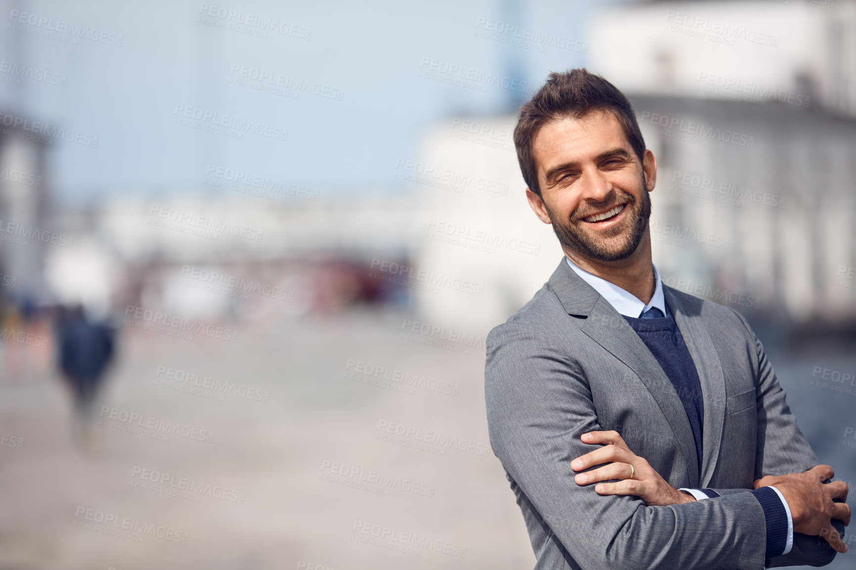 Buy stock photo Cropped portrait of a handsome young businessman standing outside alone with his arms folded during the day