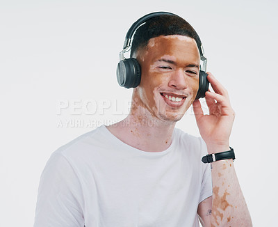 Buy stock photo Portrait shot of a handsome young man with vitiligo listening to music with wireless headphone on a white background