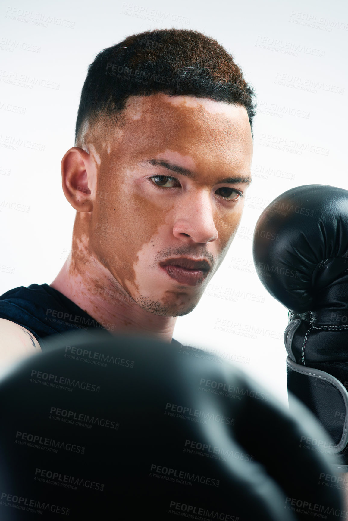 Buy stock photo Serious man, portrait and boxer with punch, vitiligo or boxing gloves for self defense on a white studio background. Young male person or tough fighter ready for MMA challenge, fight or competition