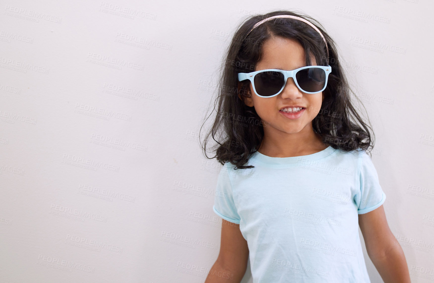 Buy stock photo Shot of an adorable little girl wearing sunglasses while standing against a wall