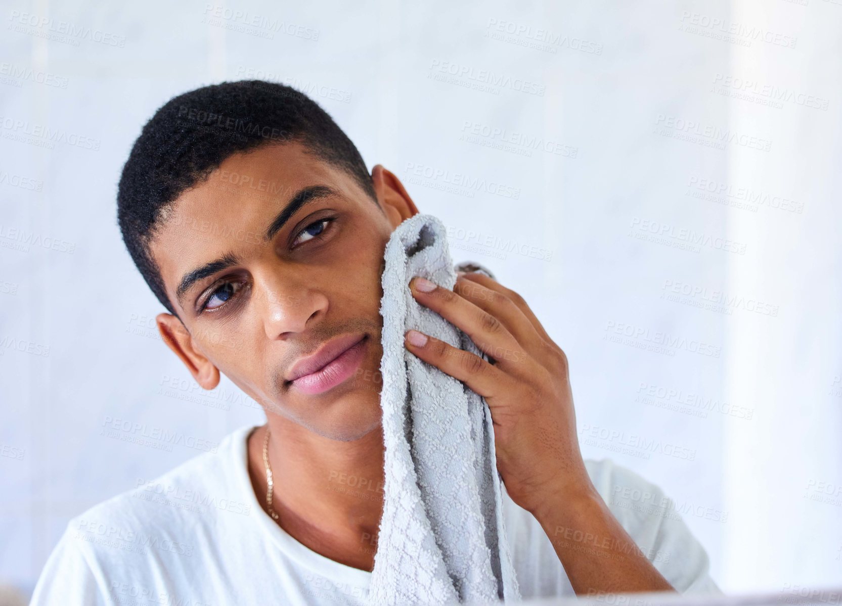 Buy stock photo Cropped shot of a handsome young man using a towel to wipe his face in the morning at home