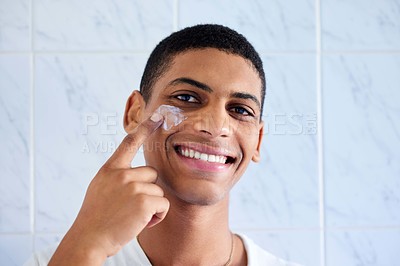 Buy stock photo Cropped portrait of a handsome young man standing alone in his bathroom and applying face cream