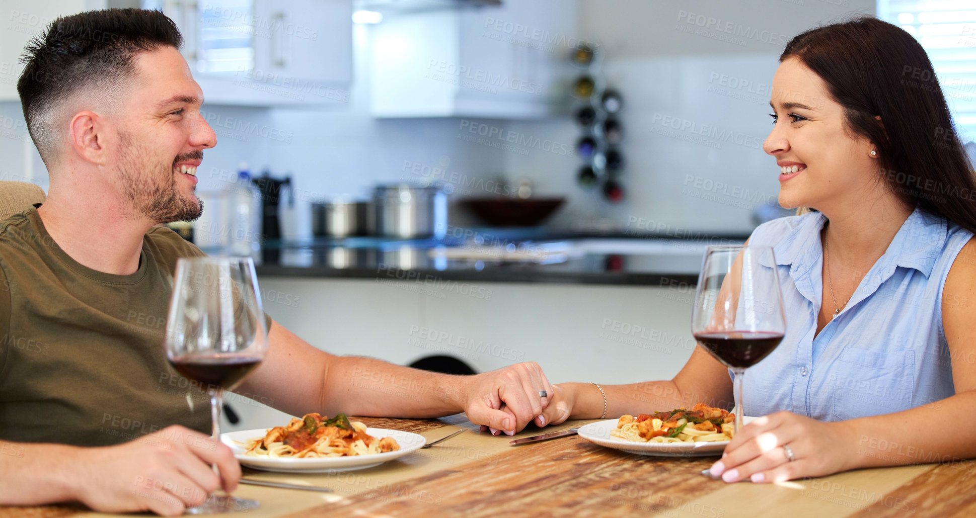 Buy stock photo Shot of a young couple having dinner in their kitchen at home