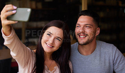 Buy stock photo Cropped shot of a young couple taking a selfie while sitting together