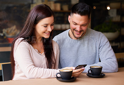 Buy stock photo Shot of a woman showing showing her boyfriend something on her cellphone while sitting in a cafe