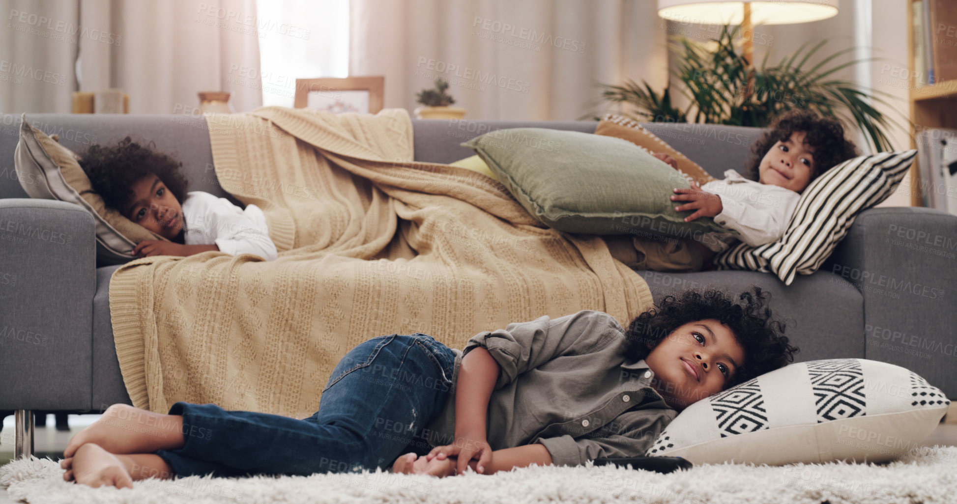 Buy stock photo Shot of three adorable little boys laying and watching tv together at home