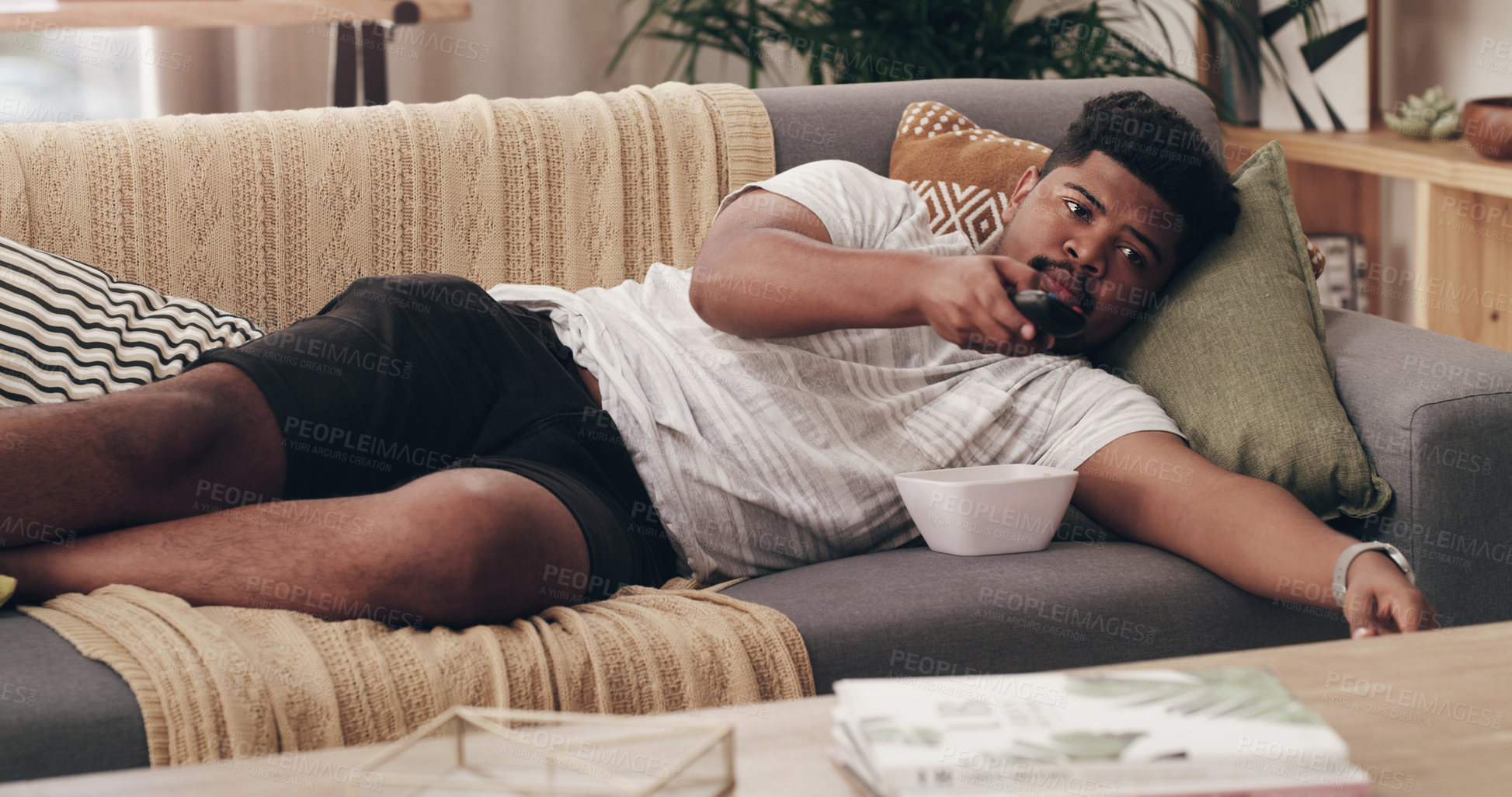 Buy stock photo Relax, lazy and a man watching tv on a sofa in the living room of his home over the weekend. Television, video and subscription streaming service to watch a movie in his house for entertainment