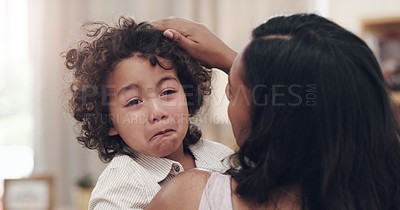 Buy stock photo Shot of an adorable boy crying while his mother comforts him at home