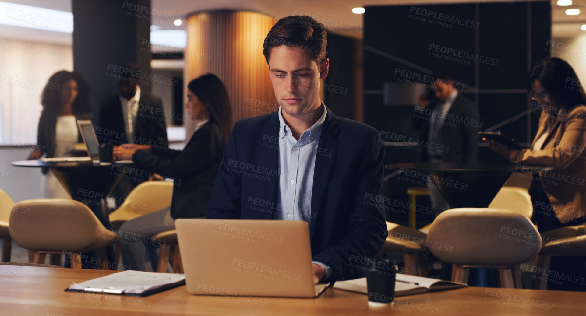 Buy stock photo Shot of a young businessman working on a laptop in an office at night