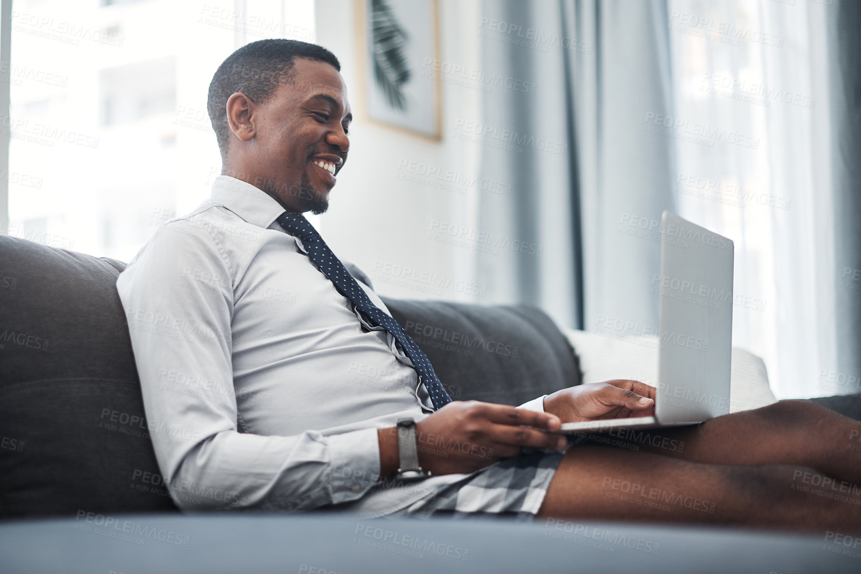 Buy stock photo Businessman, underwear and laptop on sofa in home for remote work, video call and online job interview. African professional, person and smile with tech for webinar, virtual meeting and communication