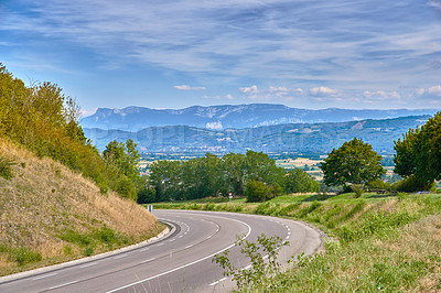 Buy stock photo Scenic countryside route on a sunny day in Summer. Empty curved road with a beautiful view of nature, and a background landscape of the farmlands, mountains and cloudy blue sky.