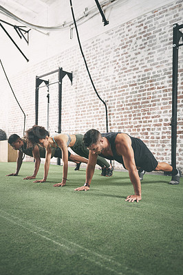 Buy stock photo Shot of a fitness group doing push-ups at the gym