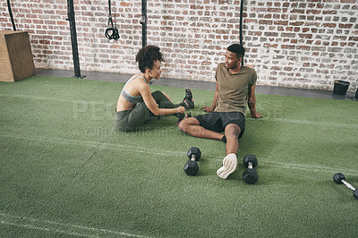 Buy stock photo Shot of two sporty young people having a conversation while sitting together at the gym