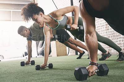 Buy stock photo Shot of a fitness group using dumbbells while doing push-ups at the gym