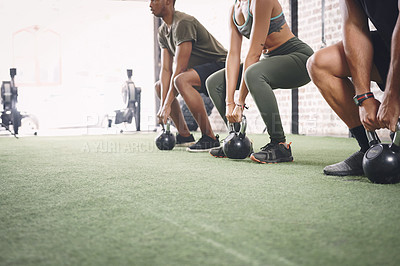 Buy stock photo Shot of a fitness group holding kettlebells while doing squats at the gym