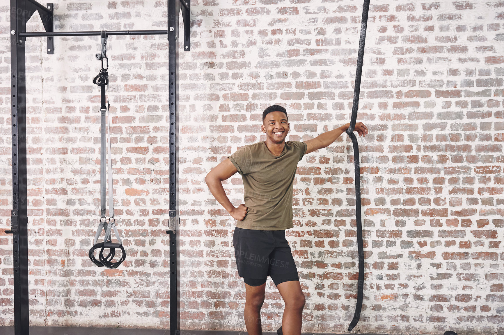 Buy stock photo Shot of a sporty young man smiling while standing in the gym