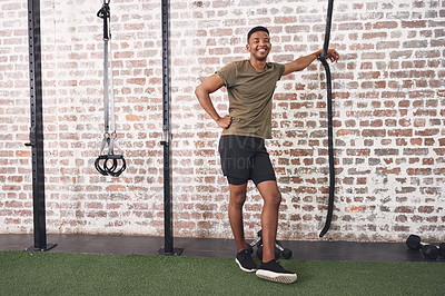 Buy stock photo Shot of a sporty young man smiling while standing in the gym