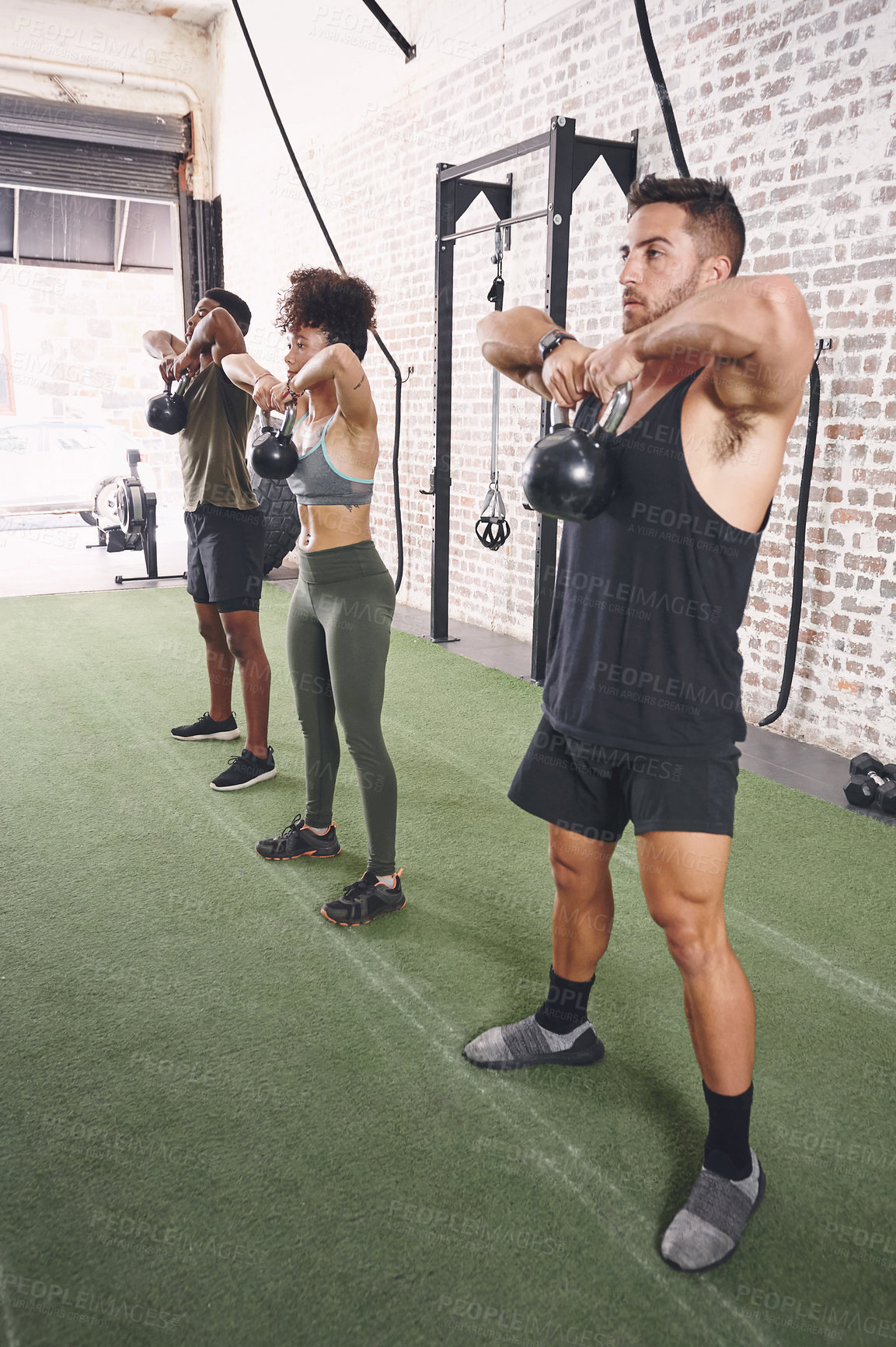 Buy stock photo Shot of a fitness group using kettlebells while working out at the gym