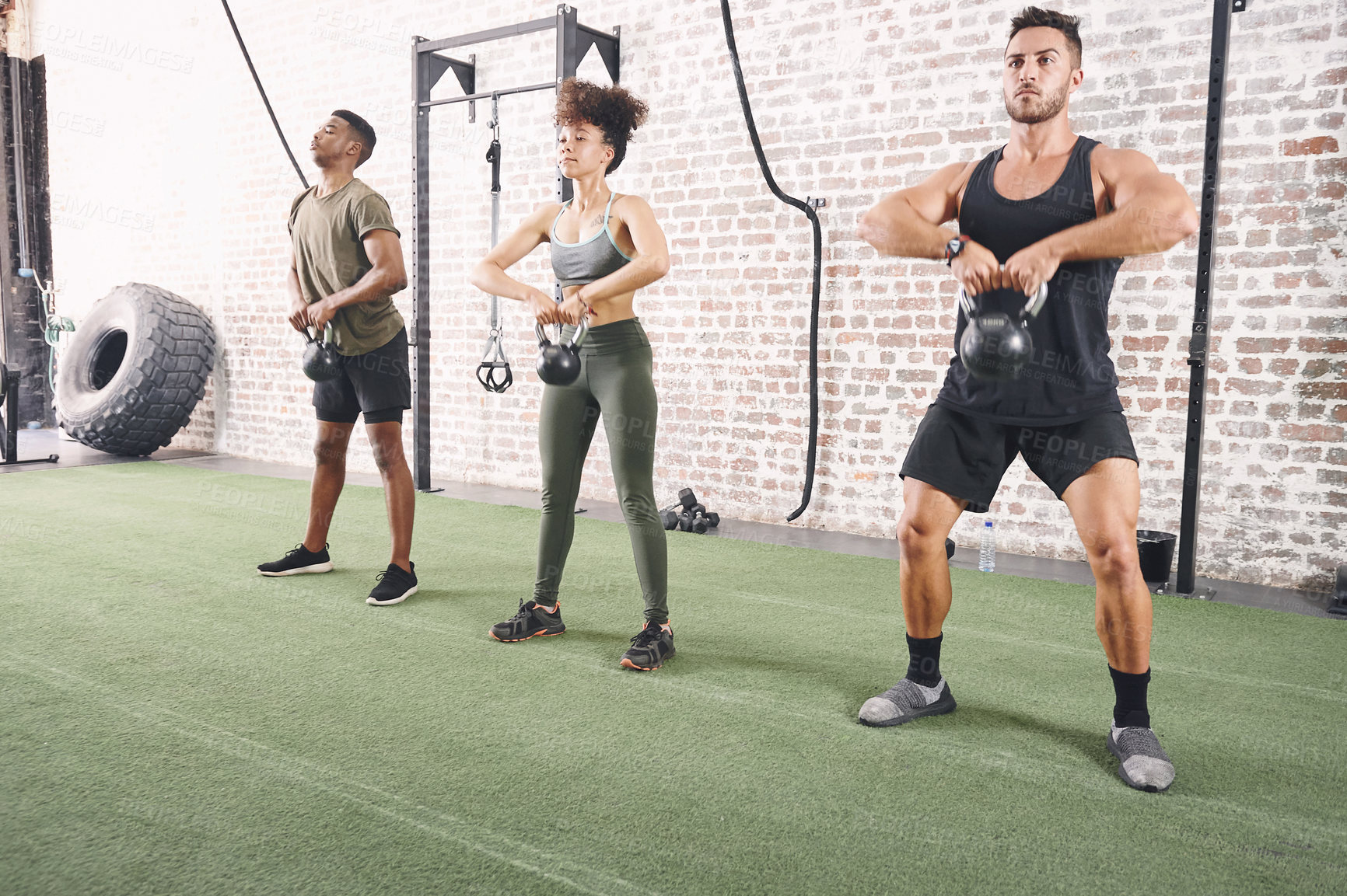 Buy stock photo Shot of a fitness group using kettlebells while working out at the gym