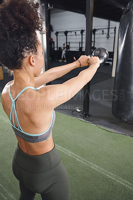 Buy stock photo Shot of a sporty young woman working out with a kettlebell at the gym