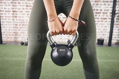 Buy stock photo Shot of a sporty young woman working out with a kettlebell at the gym
