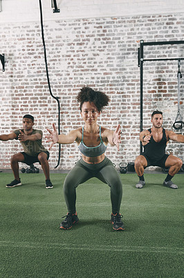 Buy stock photo Shot of a fitness group doing squats while working out at the gym