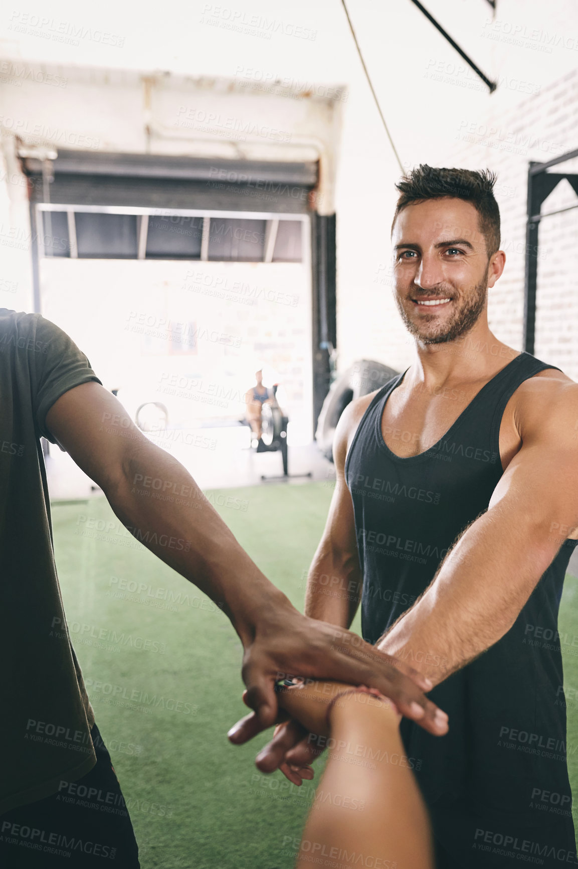 Buy stock photo Shot of three sporty young people joining their hands together in a huddle