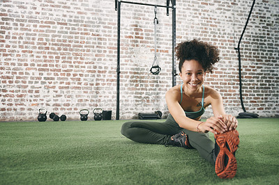 Buy stock photo Shot of a happy young woman stretching at the gym