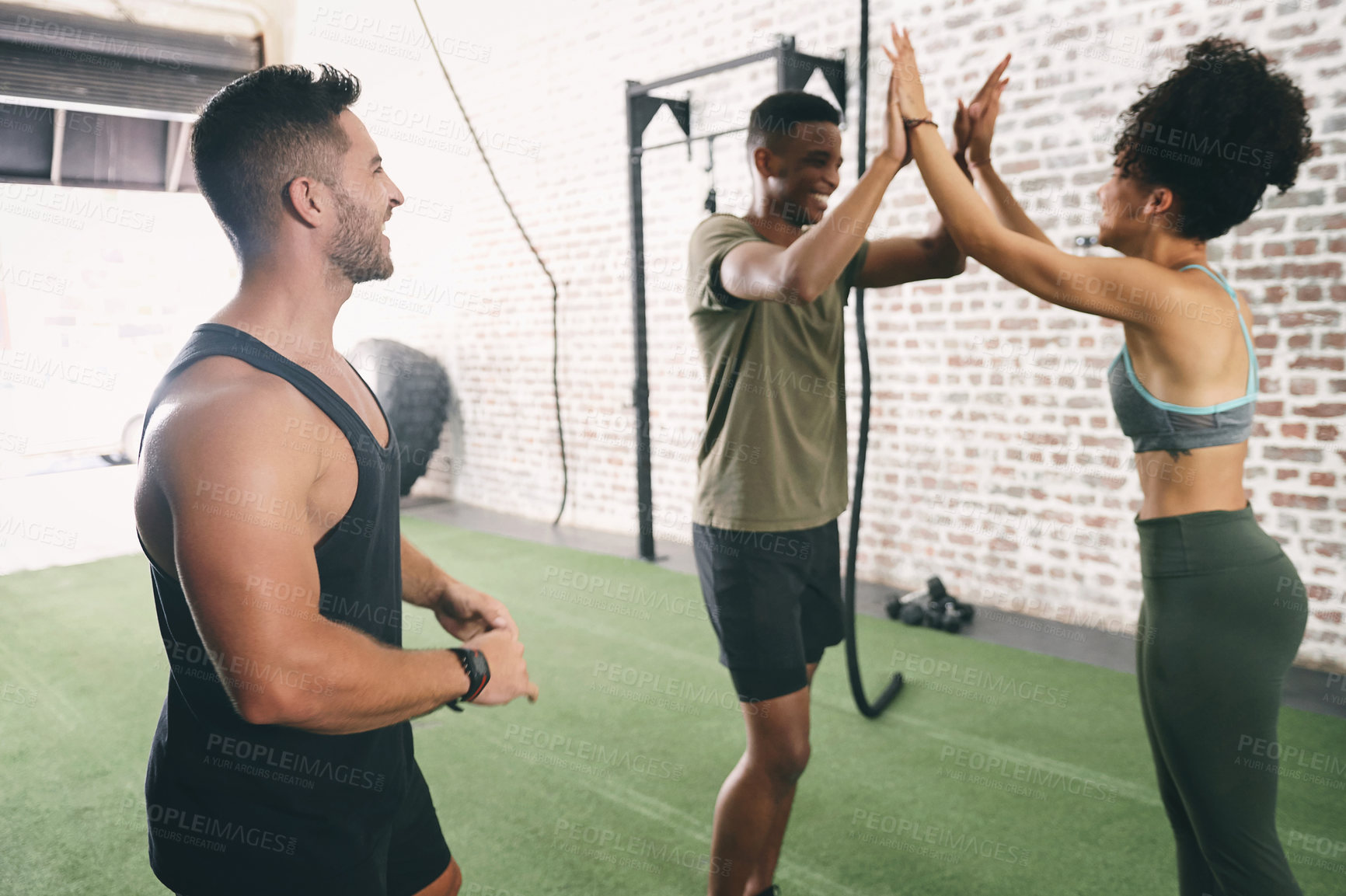 Buy stock photo Shot of three sporty young people giving each other a high five