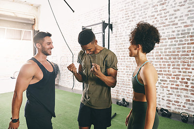 Buy stock photo Shot of three sporty young people looking cheerful at the gym