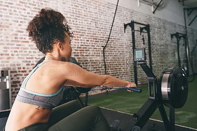 Buy stock photo Shot of a sporty young woman working out on a rowing machine