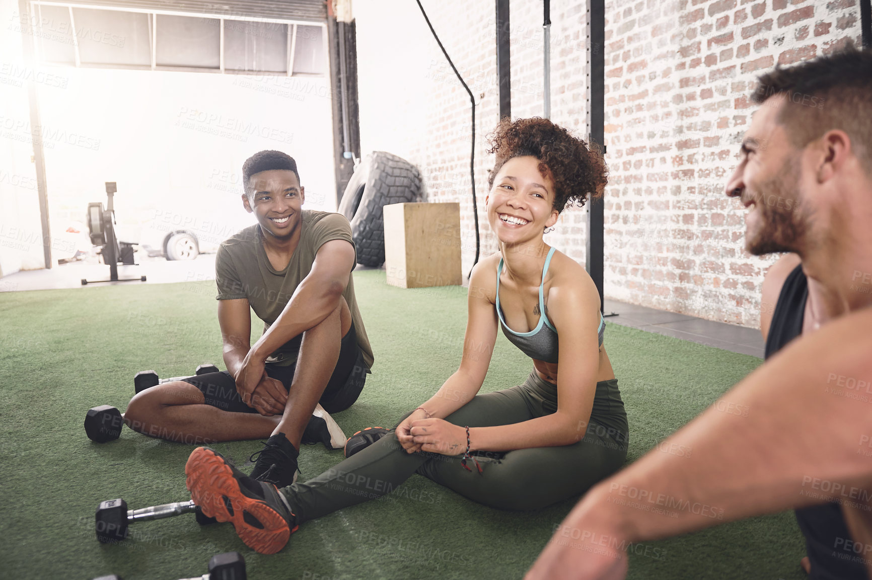Buy stock photo Shot of three sporty young people talking while sitting together in a gym