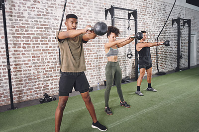 Buy stock photo Shot of a fitness group working out using kettlebells at the gym