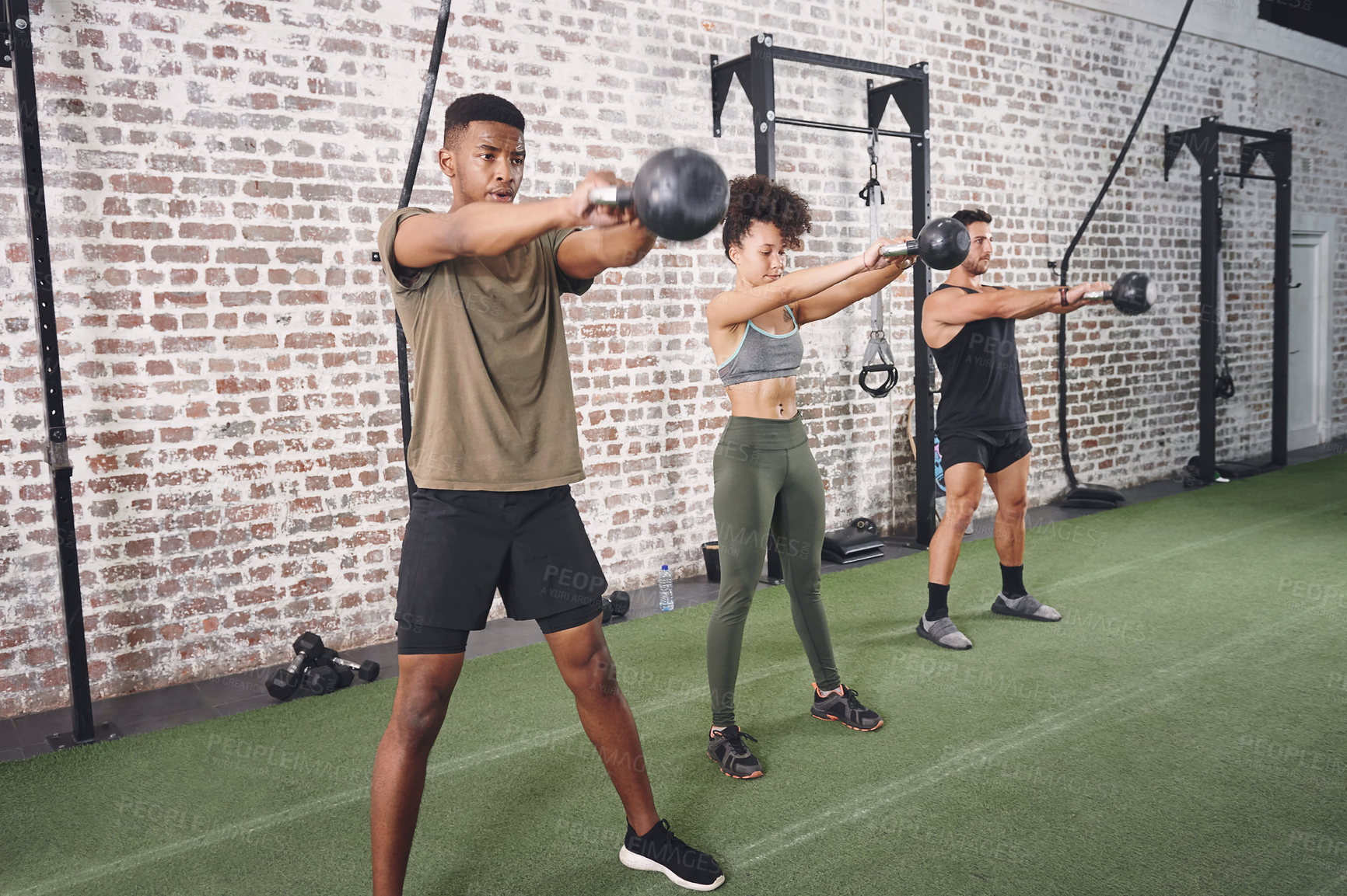Buy stock photo Shot of a fitness group working out using kettlebells at the gym