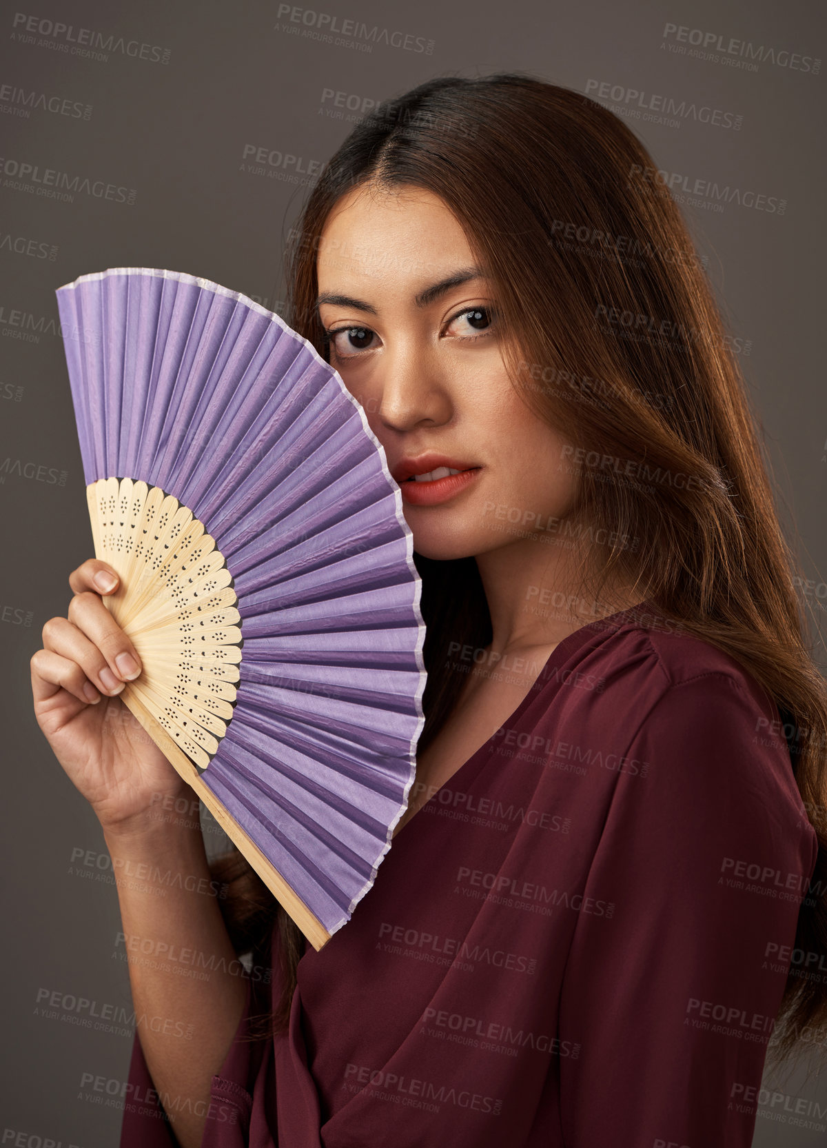 Buy stock photo Cropped portrait of an attractive young woman posing with a fan in studio against a grey background