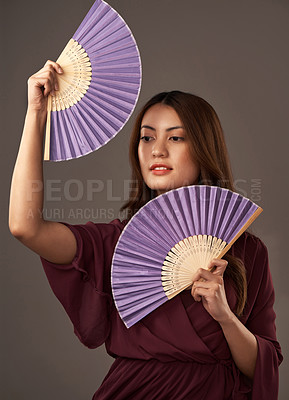 Buy stock photo Cropped portrait of an attractive young woman posing with fans in studio against a grey background