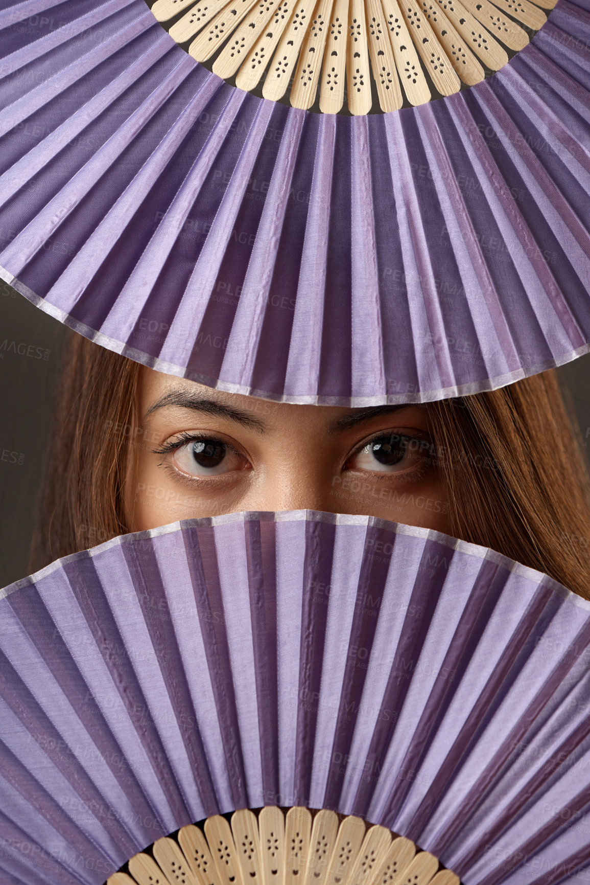 Buy stock photo Cropped portrait of an attractive young woman posing with fans in studio against a grey background