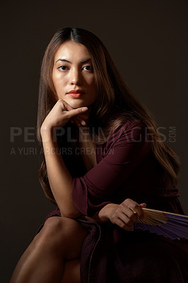 Buy stock photo Cropped portrait of an attractive young woman posing with a fan in studio against a grey background