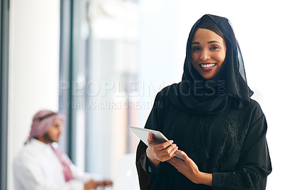 Buy stock photo Portrait of a young muslim businesswoman holding a digital tablet with her colleague working in the background