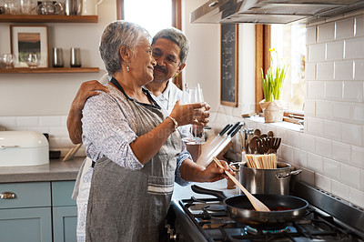 Buy stock photo Cheers, wine and old couple at in kitchen cooking food together at stove with smile, love and romance. Toast, drinks and senior woman with man, glass and happiness to make dinner meal in retirement