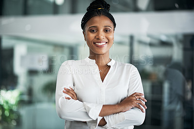 Buy stock photo Shot of an attractive young businesswoman standing alone in the office with her arms folded during the day