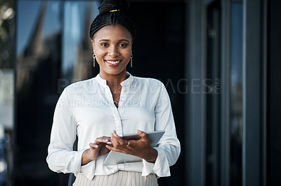 Buy stock photo Shot of an attractive young businesswoman standing alone outside and using a digital tablet during the day